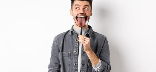 Mężczyzna używa szkła powiększającego, pokazując swój język.