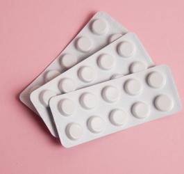 Trzy blistry tabletek na różowym tle.