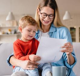 Młoda mama z małym dzieckiem przeglądają ofertę ubezpieczenia NNW dla dziecka