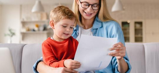 Młoda mama z małym dzieckiem przeglądają ofertę ubezpieczenia NNW dla dziecka