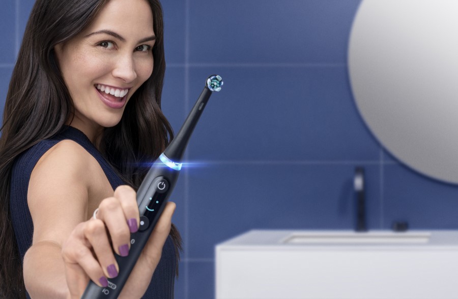 uśmiechnięta kobieta trzymająca szczoteczkę magnetyczną Oral-B iO