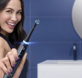 uśmiechnięta kobieta trzymająca szczoteczkę magnetyczną Oral-B iO