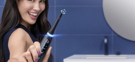 uśmiechnięta kobieta trzymająca szczoteczkę magnetyczną Oral-B iO