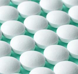 Rzędy białych tabletek na seledynowym tle.