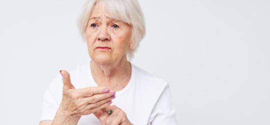 Starsza, zmartwiona kobieta zmagająca się z afazją.