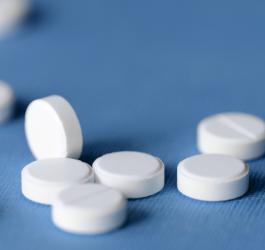 Białe tabletki na niebieskim tle.