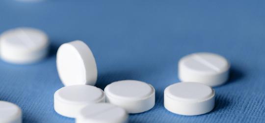 Białe tabletki na niebieskim tle.