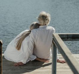 Dwie starsze kobiety siedzą na pomoście nad jeziorem.