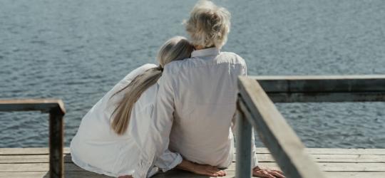 Dwie starsze kobiety siedzą na pomoście nad jeziorem.