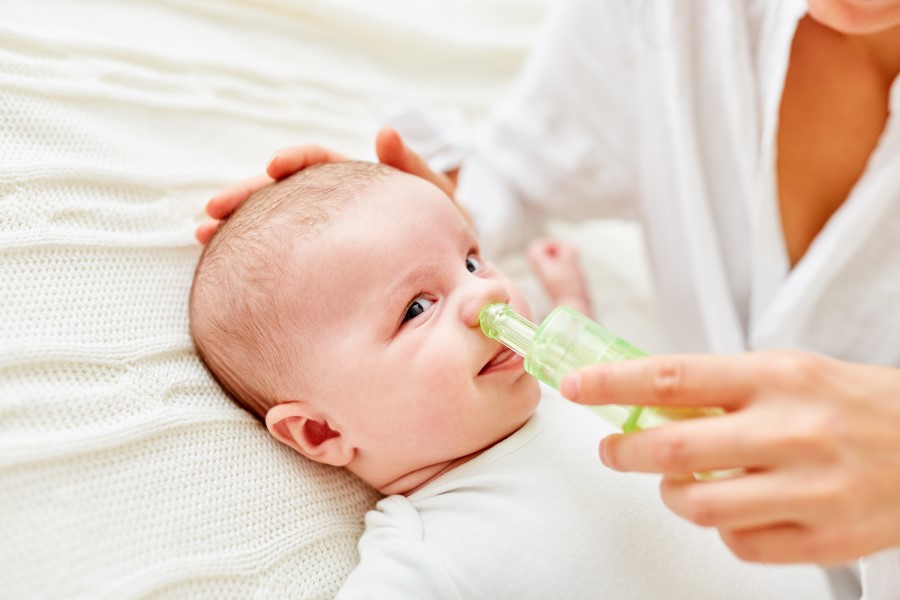 Mama oczyszcza niemowlęciu nos przy pomocy aspiratora do nosa.