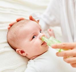 Mama oczyszcza niemowlęciu nos przy pomocy aspiratora do nosa.
