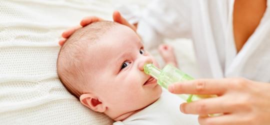 Mama oczyszcza niemowlęciu nos przy pomocy aspiratora do nosa.