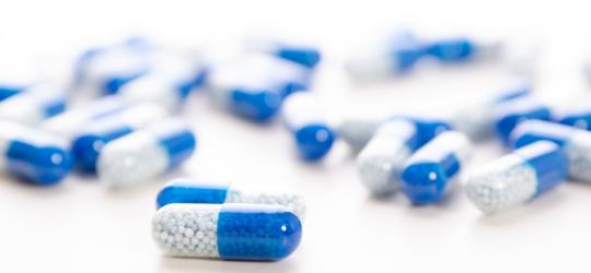Niebiesko-białe kapsułki zawierające antybiotyk azytromycynę.
