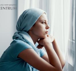 Kobieta z chustką na głowie wygląda przez okno.