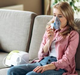 Kobieta wykonuje nebulizację z użyciem inhalatora.
