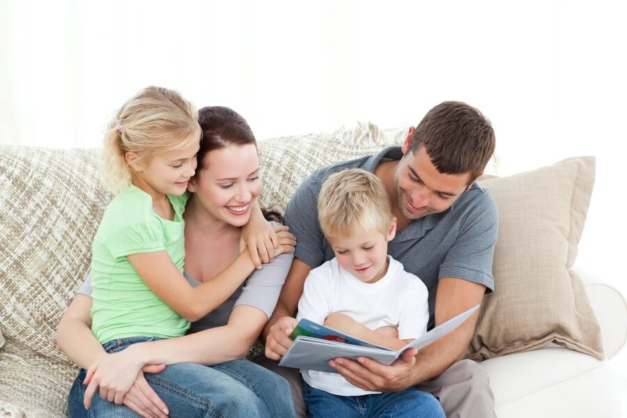 Rodzice z dwójką dzieci razem czytają książkę.