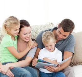 Rodzice z dwójką dzieci razem czytają książkę.