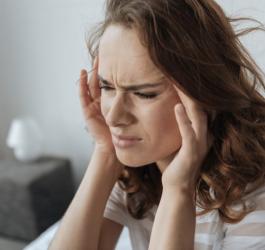 Kobieta odczuwa ból głowy przy schylaniu.