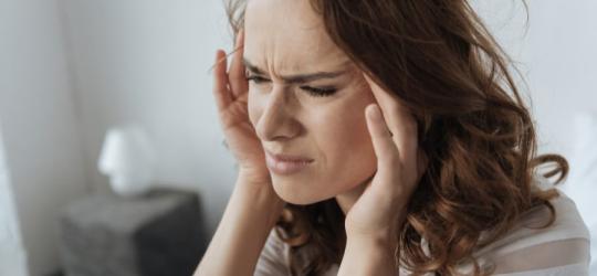Kobieta odczuwa ból głowy przy schylaniu.