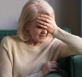 Kobieta chwyta się za czoło, odczuwa ból głowy z przodu.