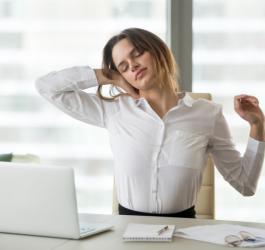 Kobieta podczas pracy przy komputerze. Boli ją szyja od nieprawidłowej pozycji podczas pracy.