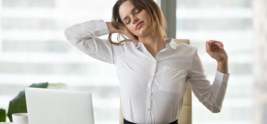 Kobieta podczas pracy przy komputerze. Boli ją szyja od nieprawidłowej pozycji podczas pracy.