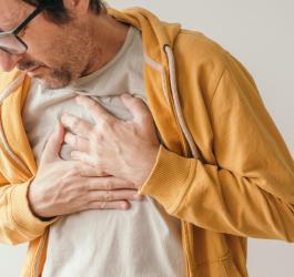 Mężczyzna odczuwa ból w klatce piersiowej, ma ręce ułożone w okolicy serca.