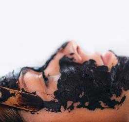 Kobieta poddaje się zabiegowi kosmetycznemu na twarz z użyciem borowiny.