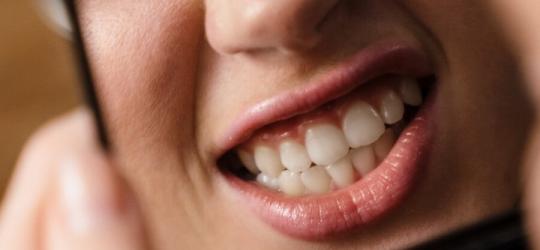 Kobieta zaciska i zgrzyta zębami, przegląda się w lusterku.