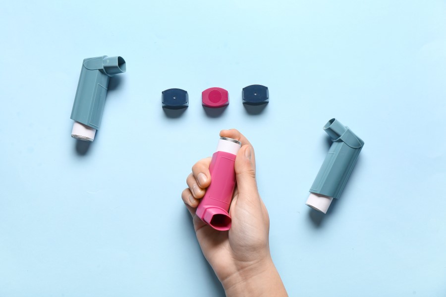 Osoba sięga ręką po budezonid w formie aerozolu.