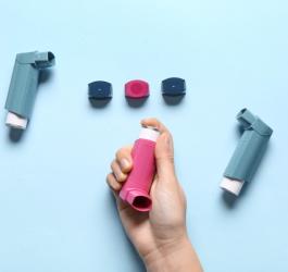 Osoba sięga ręką po budezonid w formie aerozolu.