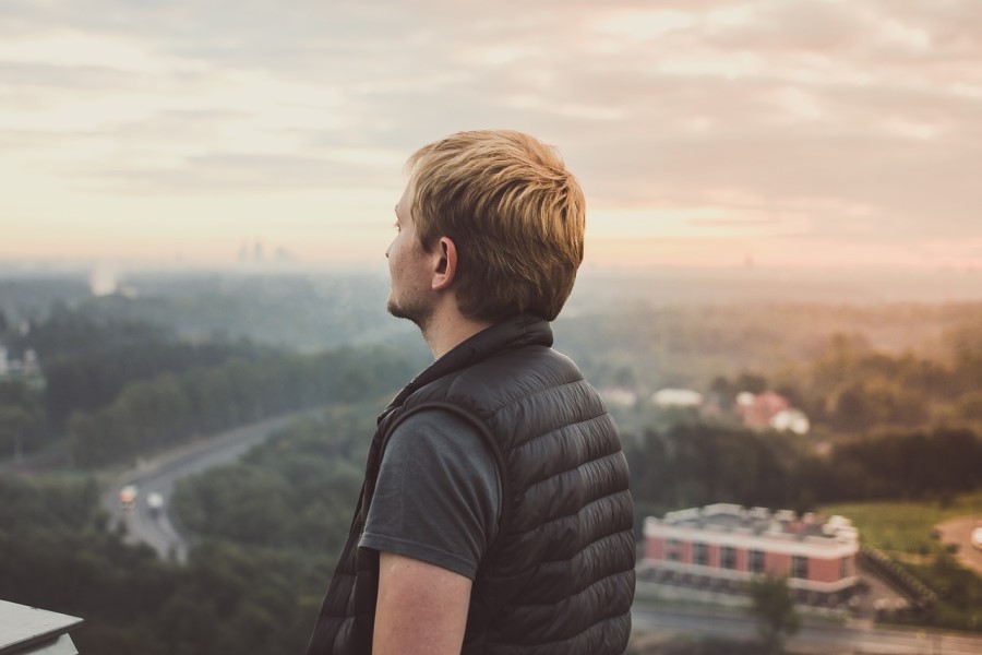Mężczyzna w kamizelce patrzy na panoramę miasta.