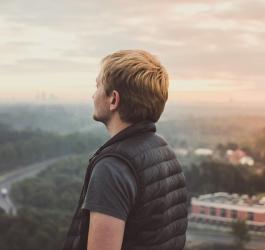 Mężczyzna w kamizelce patrzy na panoramę miasta.
