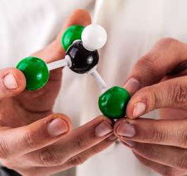 Naukowiec trzyma w dłoniach model budowy chloroformu.