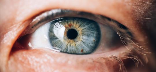 Zbliżenie na ludzkie oko z niebieską tęczówką.