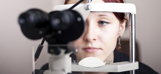 Kobieta w trakcie badania okulistycznego, będącego częścią diagnostyki chorób oczu.