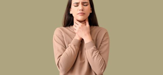 Kobiecie dokucza chrypka, trzyma się za szyję.