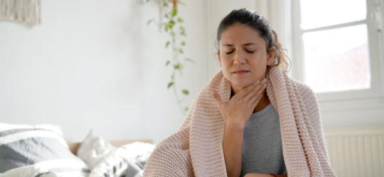 Kobieta trzyma się za szyję, dokucza jej ciągłe drapanie w gardle.