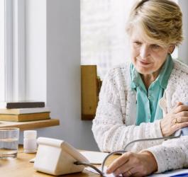 Starsza kobieta mierzy ciśnienie krwi ciśnieniomierzem naramiennym.