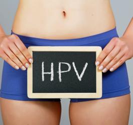Kobieta w bieliźnie, na wysokości bioder trzyma niewielką tablicę kredową z napisem HPV.