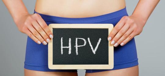 Kobieta w bieliźnie, na wysokości bioder trzyma niewielką tablicę kredową z napisem HPV.