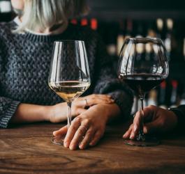 Kobiety w winiarni piją białe i czerwone wino z wysokich kieliszków.