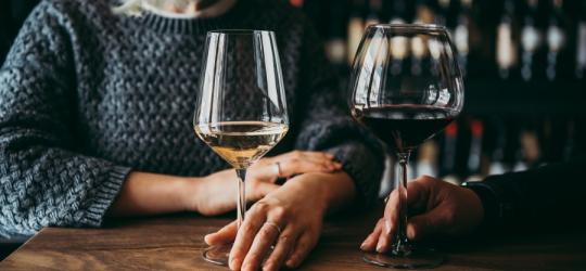 Kobiety w winiarni piją białe i czerwone wino z wysokich kieliszków.