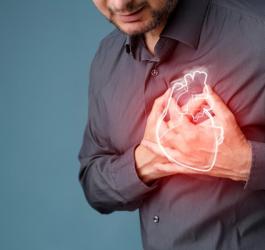 Mężczyzna kurczowo trzyma się za klatkę piersiową, w której odczuwa ból.