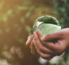 Kobieta trzyma w dłoniach dużą, szklaną kulę.