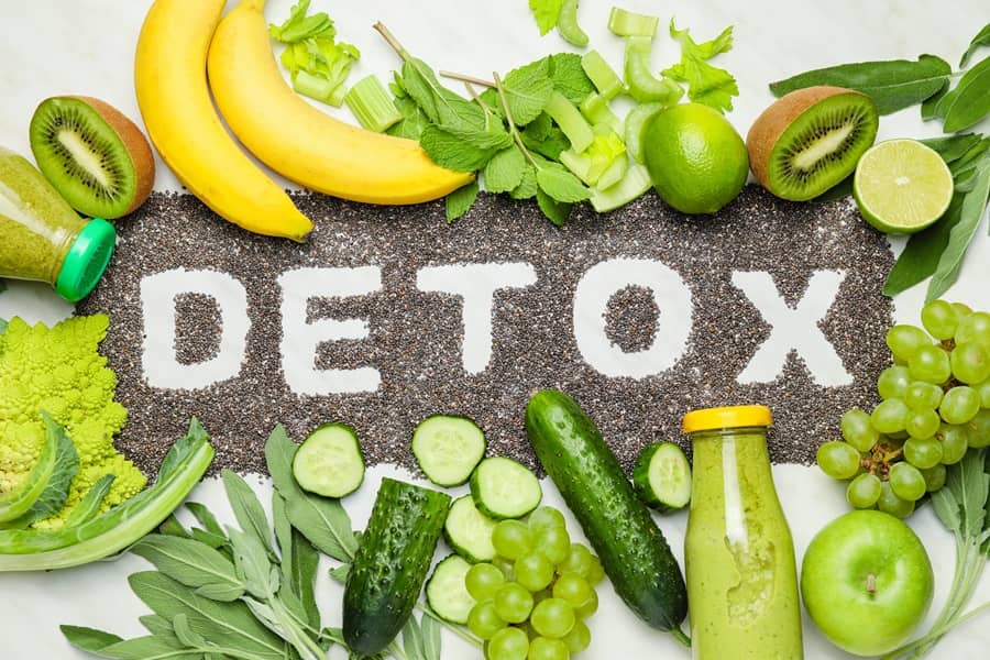 Świeże warzywa i owoce, rozsypana nasiona chia z napisem DETOX.