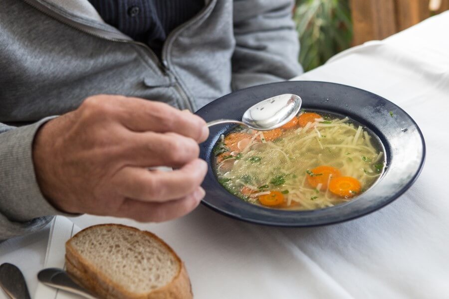 Starsza osoba zjada lekki posiłek zgodny z zasadami diety lekkostrawnej.