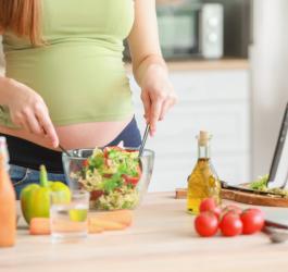 Ciężarna kobieta przygotowuje dla siebie wegański posiłek.