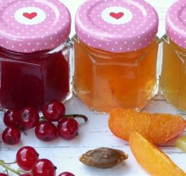 Słoiczki zawierające przetwory z owoców sezonowych. Obok leżą świeże owoce.