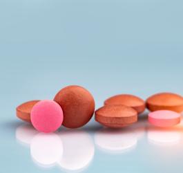 Czerwone i różowe tabletki na niebieskim tle.